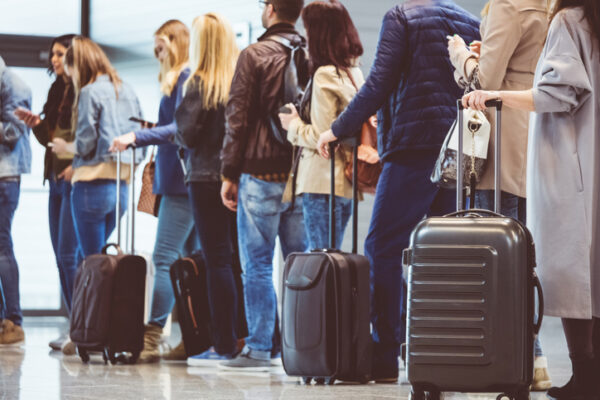 green card travel risks line of travelers at an airport